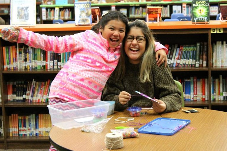 1 adult female mentor with girl mentee in library