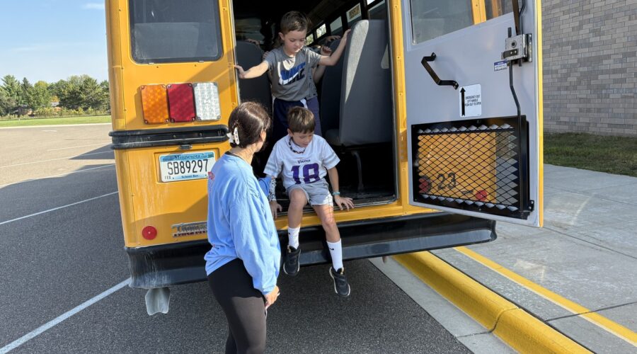 A student at Greenvale Park Elementary exits the bus from the emergency exit with the help of a teacher while practicing bus safety.