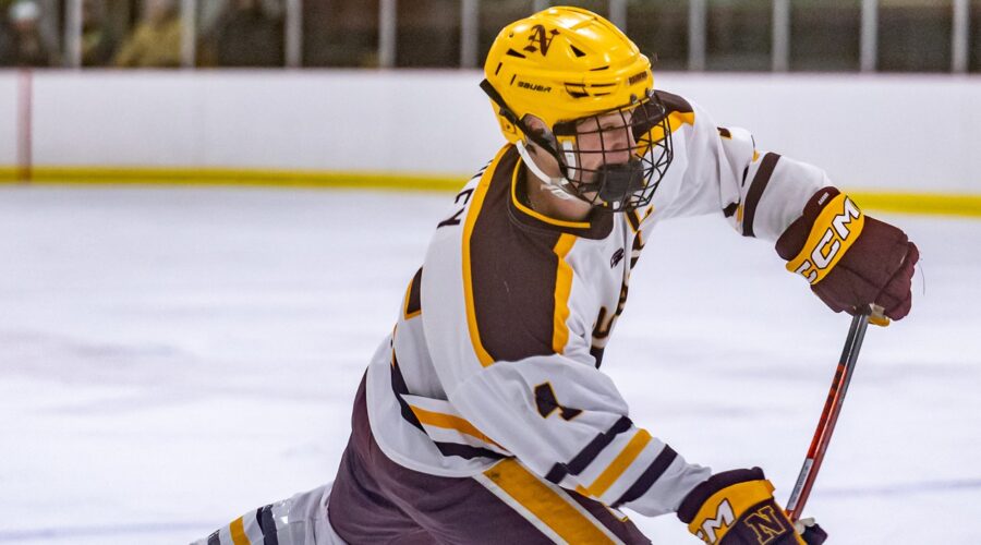 An NHS hockey player skates on the ice and appears ready to hit the puck.